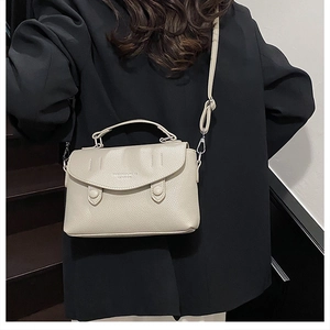 Detail of off-white lychee grain leather crossbody bag with flap and dual round buttons