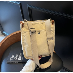 Dettaglio borsa tote in tela beige con tracolla regolabile e tasca con bottone