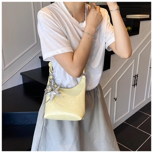Détail d'un sac seau jaune clair brillant avec un charmant pendentif étoile de mer argent