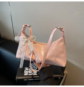 Detail of pink patent leather handbag with pearl lace bow and adjustable silver buckle