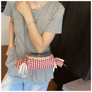 Detailed view of candy-shaped red plaid bag with lace trim and silver chain strap