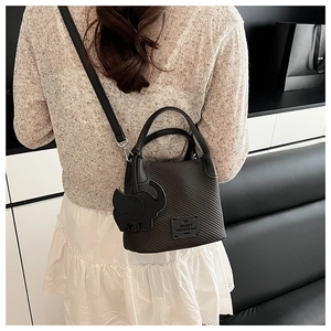 Close-up of black lychee texture bucket bag with cute elephant charm and slim strap
