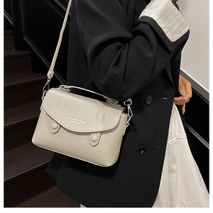 Detail view of beige lychee pattern leather square bag featuring double button accents
