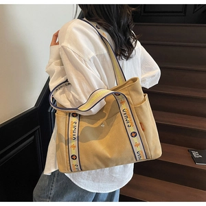 Detail of khaki canvas tote bag with jacquard shoulder strap on wooden stairs