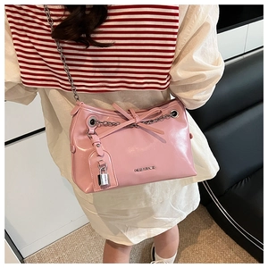 Detail shot of a pink patent leather shoulder bag with a metal chain and bow accent