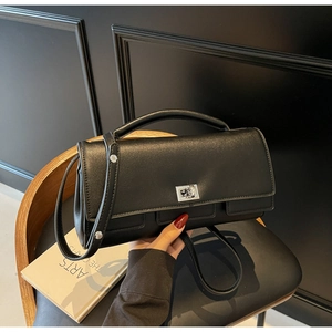 Detail of structured black leather handbag with silver twist lock and top handle