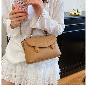 Close-up of brown lychee grain leather crossbody bag worn by a model in casual style