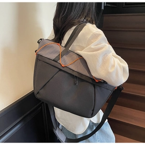 Detail view of the checkerboard patterned flap and orange elastic cord on the shoulder bag