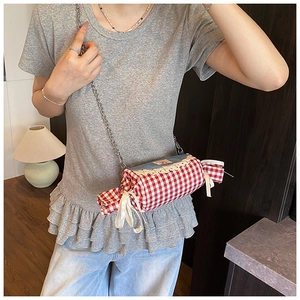 Detail of candy-shaped plaid bag with lace trim, denim top and silver chain strap