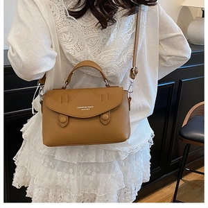 Detail of a brown leather shoulder bag with lychee texture and metal clasp