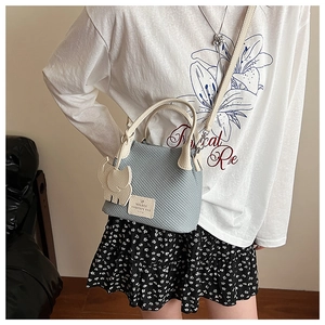 Detail of light blue lychee texture bucket bag with cute elephant charm and leather handle