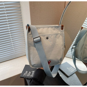 Dettaglio borsa tote blu in tela con tracolla larga e rifiniture in pelle marrone