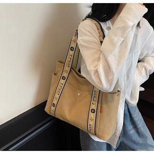 Detail of khaki canvas tote bag with wide jacquard strap and side pocket feature