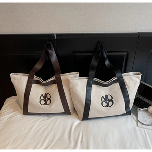 Detail view of two large canvas tote bags with leather trim and NOCO logo branding