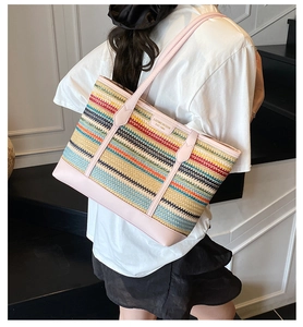 Detailed side view of a colorful woven straw tote bag with pink leather shoulder straps