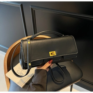Close-up of minimalist black leather handbag featuring a golden twist lock closure