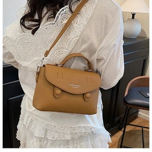 Detail of caramel lychee grain leather crossbody bag with top handle and fashion logo