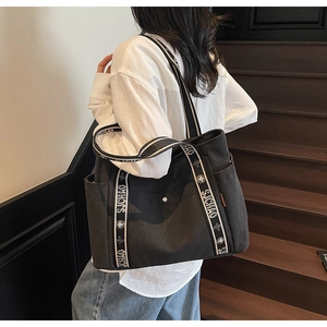 Detail of dark grey canvas tote bag featuring contrast straps and functional front buckle pocket