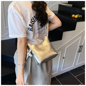 Détail du sac à bandoulière argenté plissé avec breloque étoile et sangle nouée