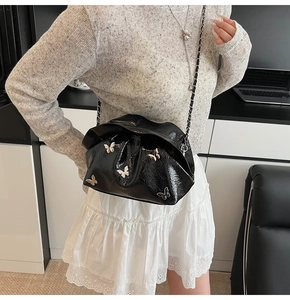 Detailed macro view of black pleated bucket bag with silver butterfly metal charms