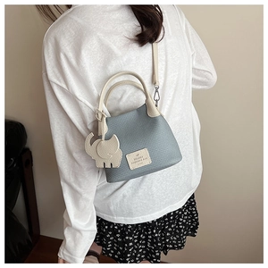 Sky blue woven bucket bag with beige top handle and a cute leather elephant charm