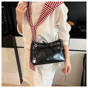 Détail d'un sac à bandoulière noir brillant avec chaîne argentée et pendentif cadenas