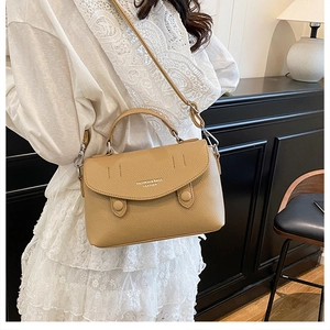 Detail of beige lychee pattern leather shoulder bag with silver hardware and logo