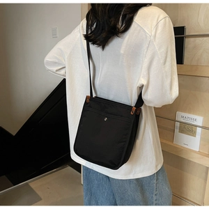 Dettaglio della borsa a tracolla in nylon nero con bottone argentato e finiture in pelle