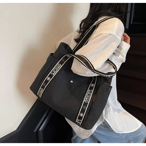 Detail of black canvas tote bag featuring striped SJCHAO handles and large capacity