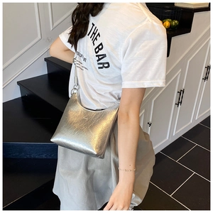 Détail du sac demi-lune argenté montrant sa texture plissée et sa fine bandoulière