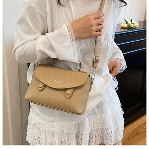 Close-up of khaki pebbled leather shoulder bag with circular buckles and fashion text