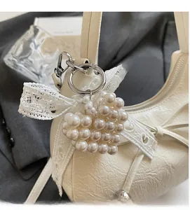 Détail d'un pendentif cœur en perles avec nœud en dentelle sur un sac en cuir