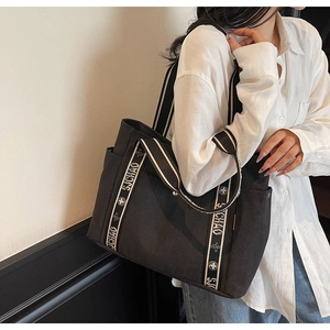 Detail of black canvas tote bag with striped straps and SJCHAO decorative lettering