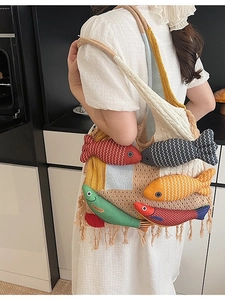 Knitted tote bag with 3D colorful fish charms and fringe tassels shown on shoulder