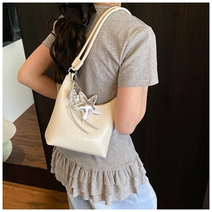 Détail d'un sac à bandoulière crème plissé orné d'un pendentif en forme d'étoile argentée