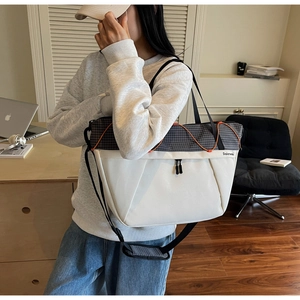 Detail of multi-compartment canvas tote bag with orange bungee cord and grid pattern
