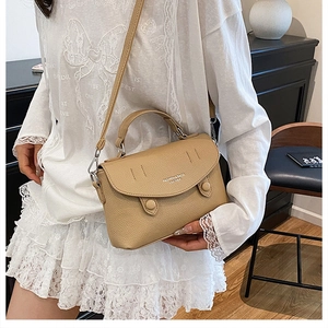 Detail of camel lychee pattern handbag featuring a round flap and adjustable strap