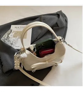 Détail de la capacité intérieure du sac croissant blanc crème avec nœud et perle