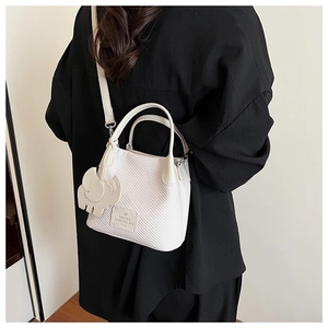 Detailed close-up of a white woven tote bag with adjustable strap and elephant charm