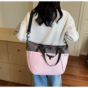 Close-up of pink and grey paneled large capacity sports tote bag worn by a model