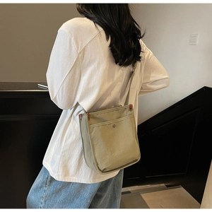 Dettaglio di una borsa tote in tela kaki con borchie in metallo e accenti in cuoio