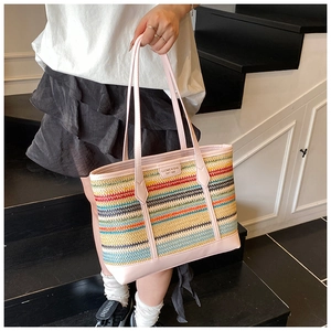 Detail of colorful woven straw tote with leather handles and luxury brand tag