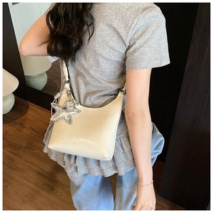 Sac hobo chic blanc crème en cuir verni brillant avec breloque étoile porté à l'épaule