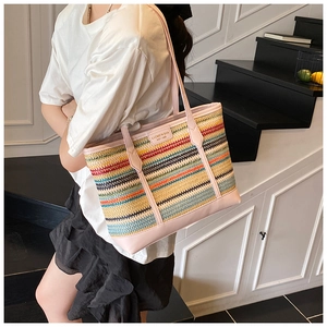 Detail of multi-color striped straw tote bag with pink leather handles and branded logo