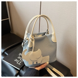 Detail of light blue woven bucket bag with cream leather trim and cute elephant charm
