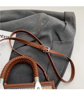 Detail of adjustable leather strap and woven handle on modern brown shoulder bag
