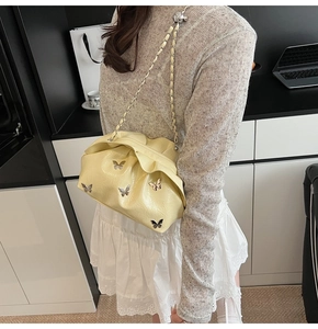 Detailed view of cream yellow bucket bag with butterfly charms and silver chain strap