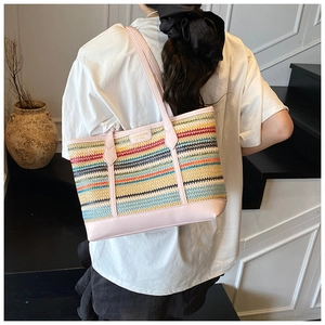 Detailed shot of large woven straw tote bag with colorful stripes and pink leather trim