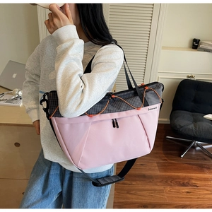 Detailed view of women's crossbody bag with pink and grey plaid patchwork and orange drawstring