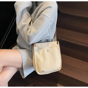 Dettaglio della borsa tote in tela crema con ampia tracolla e tasca frontale esterna